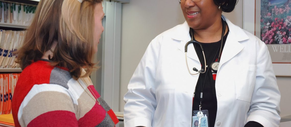 Woman speaking to Doctor in Doctors office.